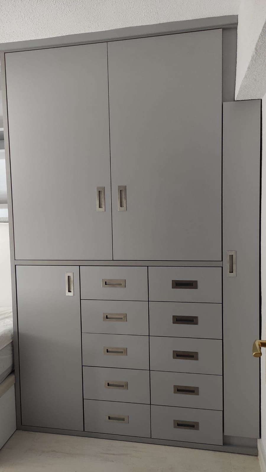 Un gran armario gris con cajones y puertas en una habitación.