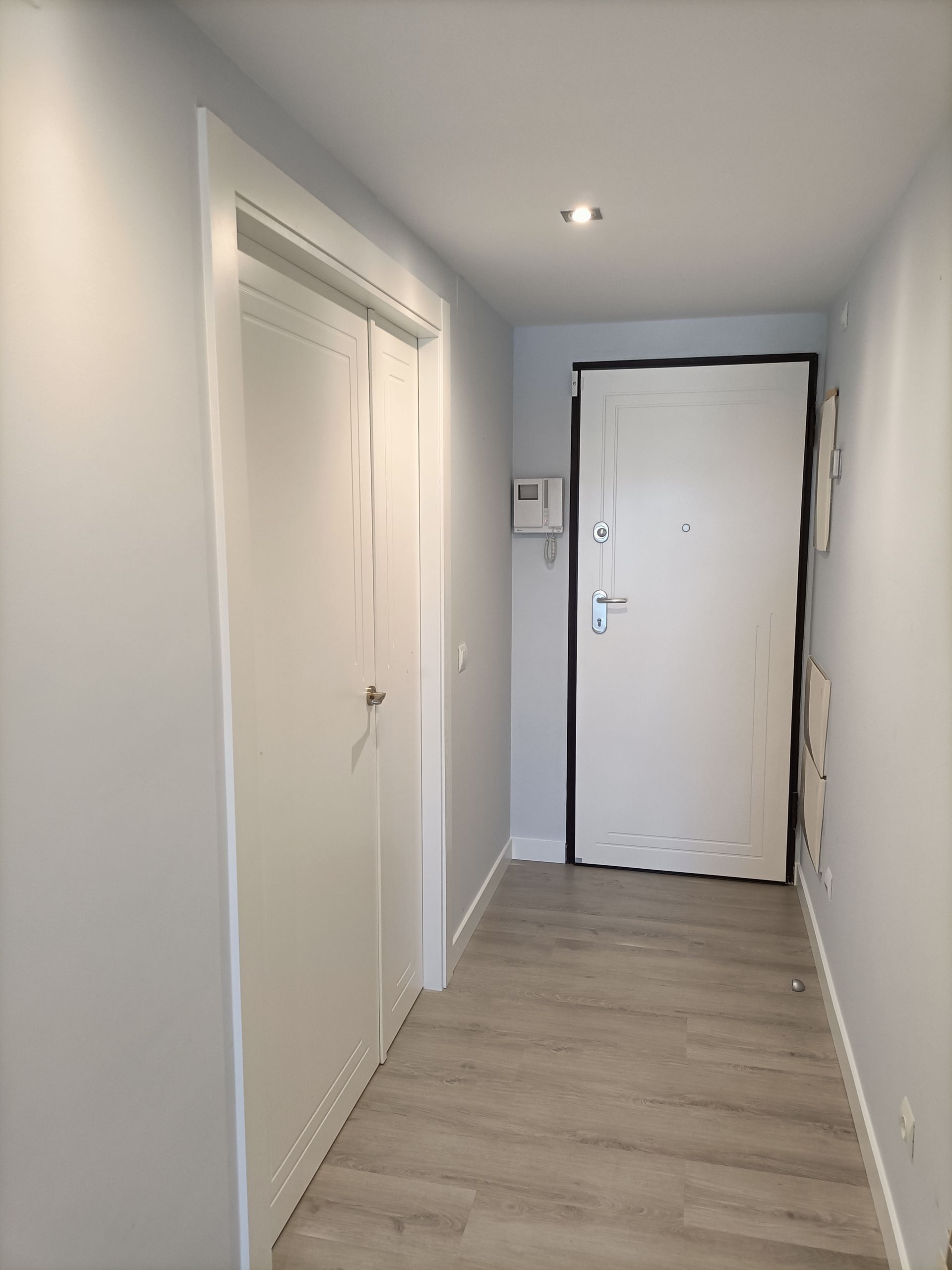 Un pasillo con paredes blancas y una puerta blanca.