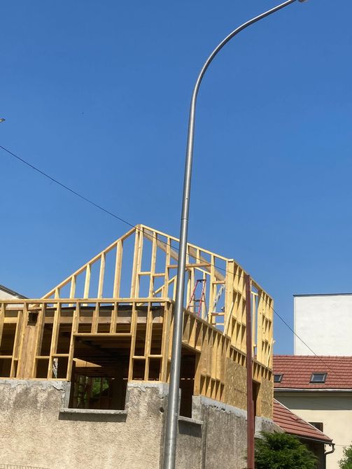 Intérieur d'un chantier de construction avec poutres apparentes, une échelle, des échafaudages et des murs inachevés.