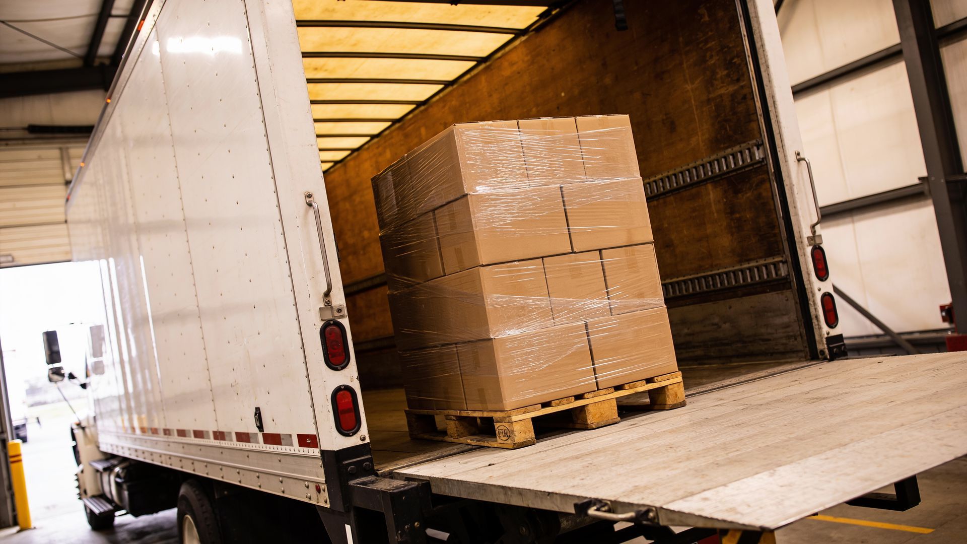 Camion de transport ouvert avec des cartons empilés sur une palette à l’intérieur de la remorque.