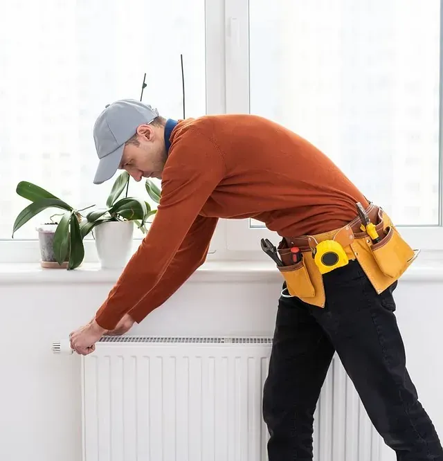 Un hombre que lleva un sombrero está trabajando en un radiador.