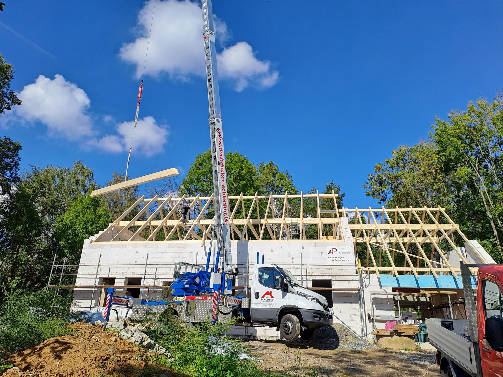 Große Baustelle mit Kran und neu errichtetem Dachstuhl auf einem Gebäude.