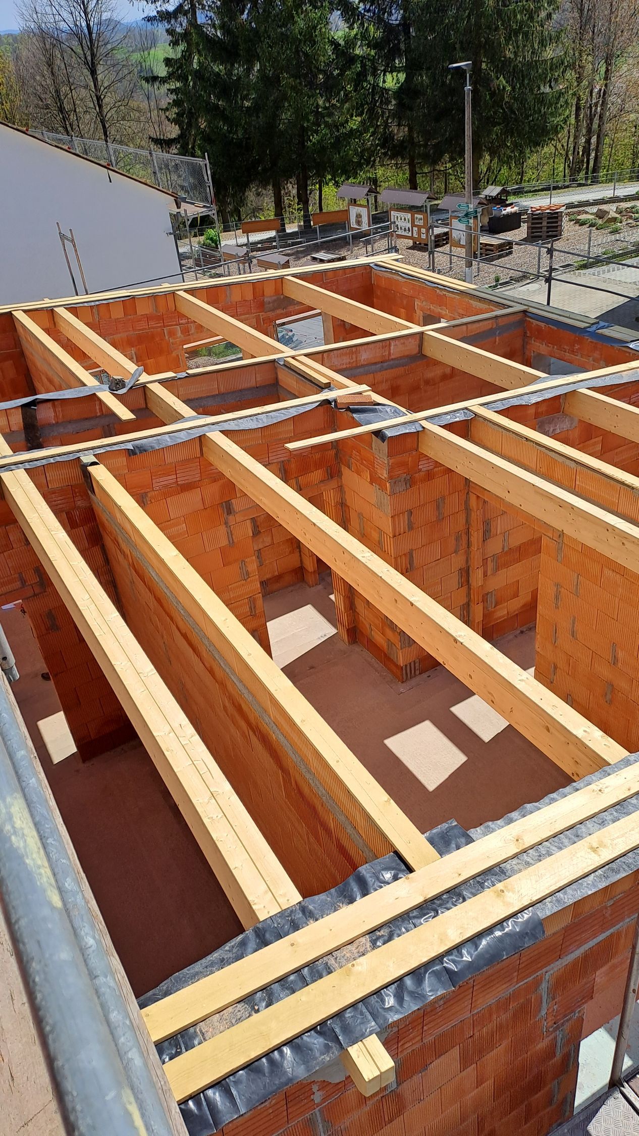 Deckenbalken aus Holz auf einem Rohbau aus Ziegeln mit integrierten Metallträgern.