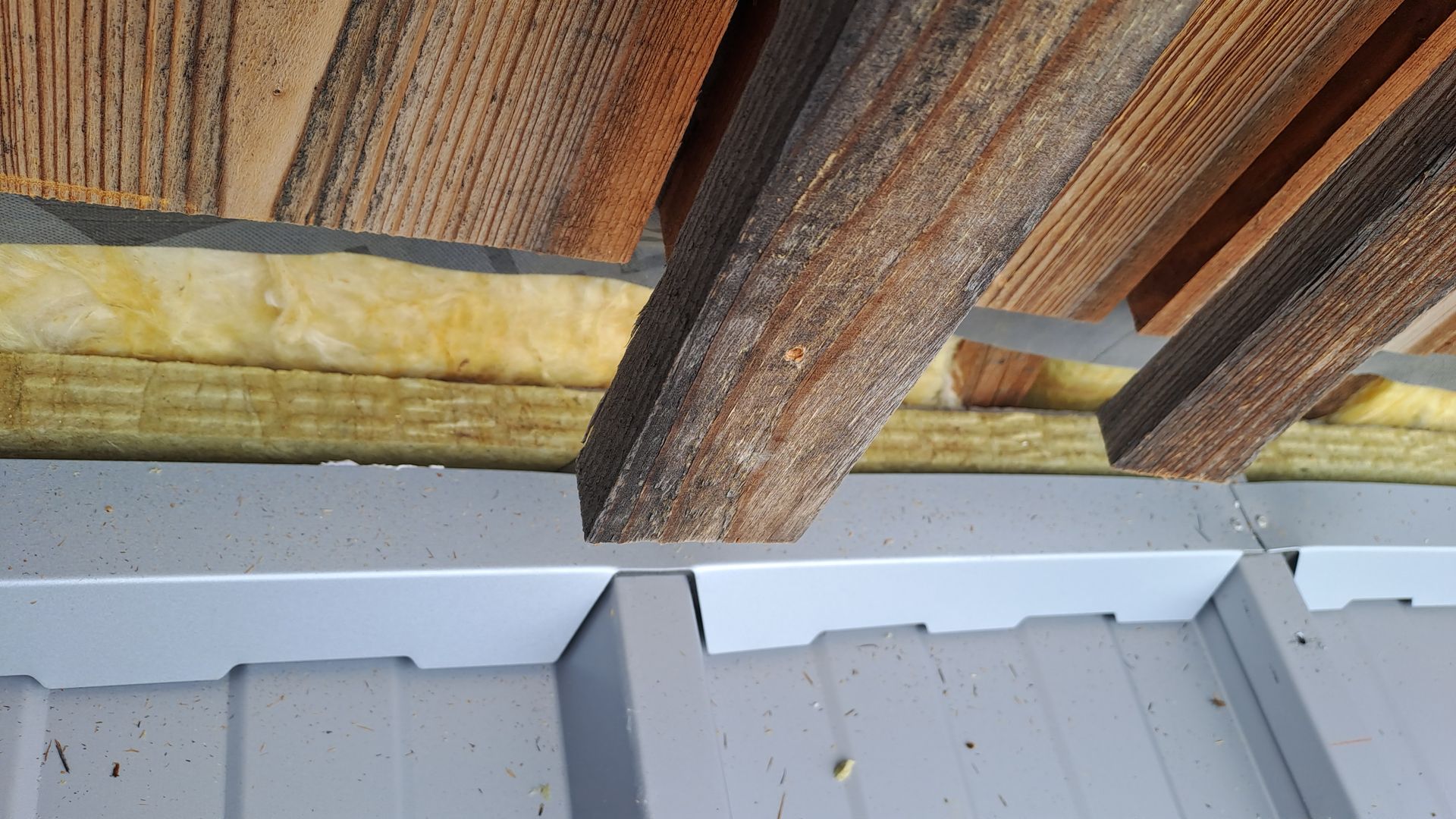 Detailansicht von Trapezblech mit Dämmung und Holzunterkonstruktion im Querschnitt.