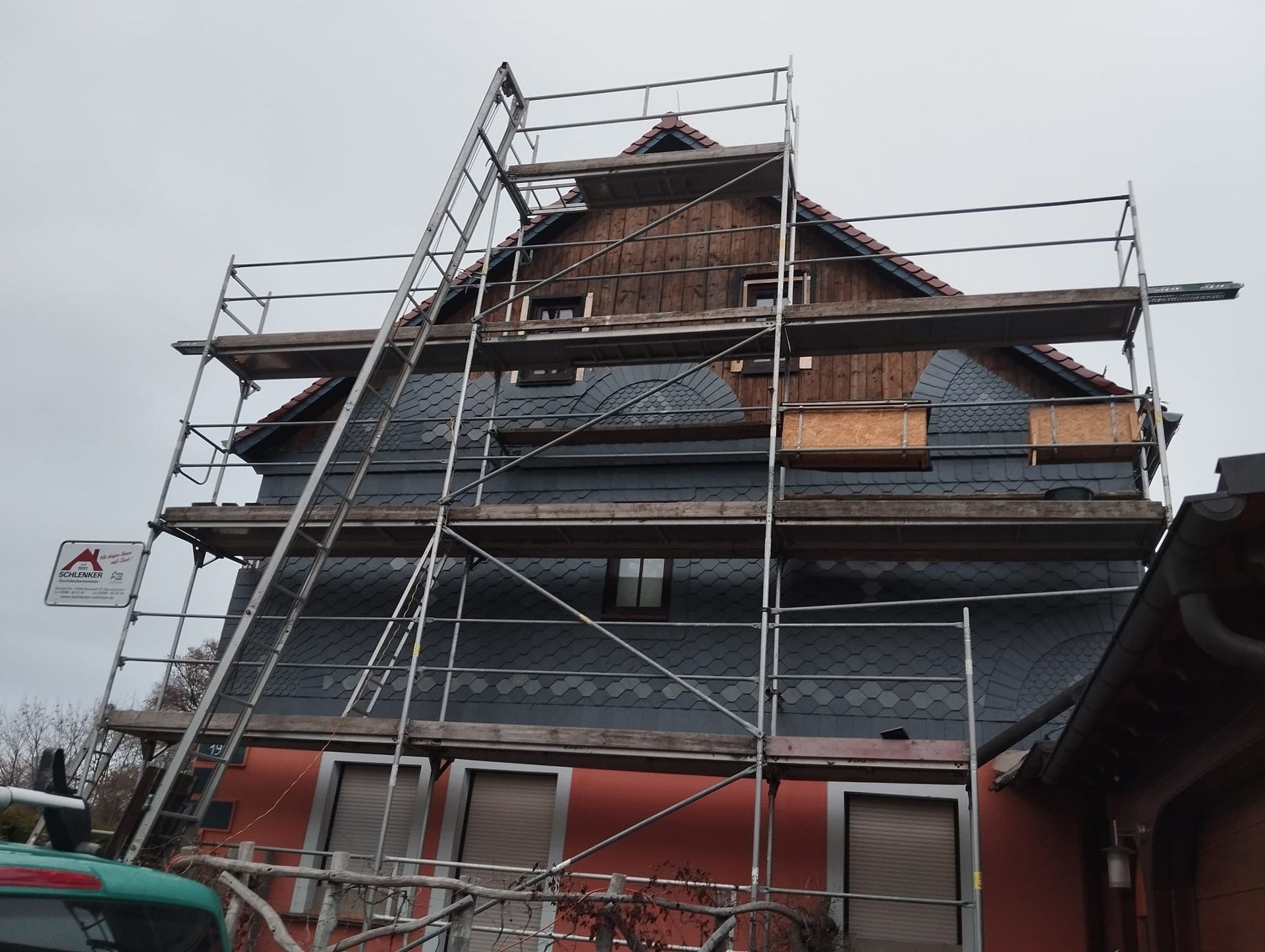 Haus mit eingerüsteter Fassade während Schieferarbeiten, Sanierung von Dach und Giebel mit Naturschiefer