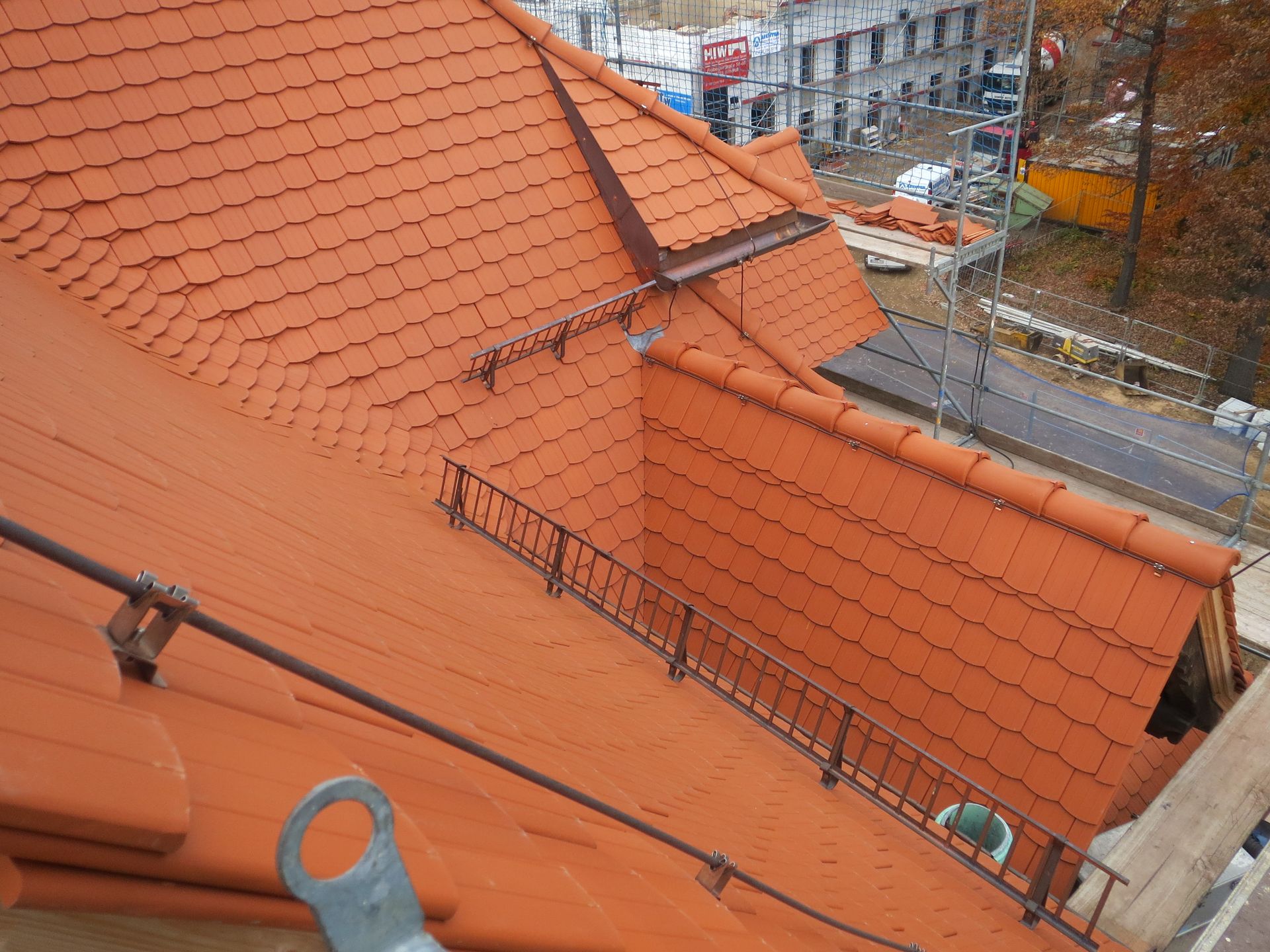 Detailansicht eines sanierten Ziegeldachs mit Dachfenster, Schneefangsystem und Dachdeckerarbeiten