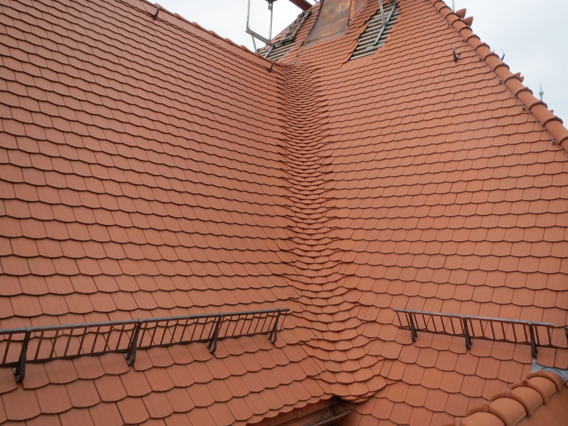 Fertiggestelltes Dach mit Biberschwanzziegeln und Schneefanggittern, gleichmäßige Dachdeckung nach Sanierung