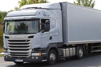 Ein weißer Scania-Sattelschlepper fährt eine Straße entlang.
