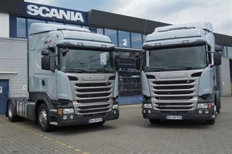 Zwei Sattelschlepper von Scania stehen vor einem Gebäude.