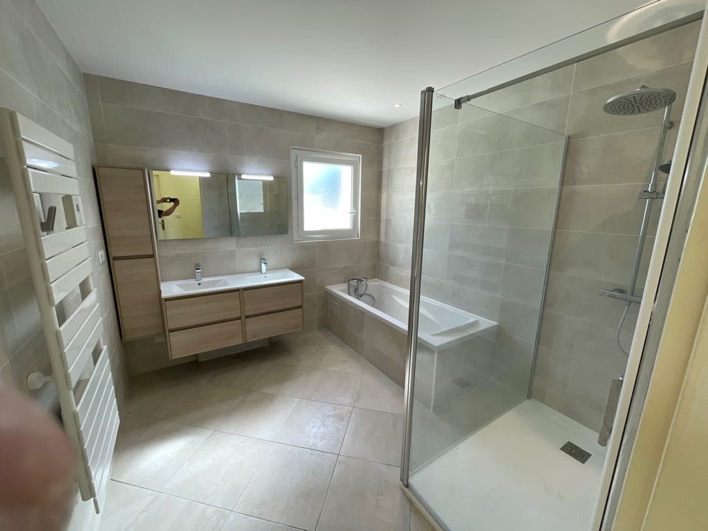 Salle de bains rénovée avec baignoire et douche.