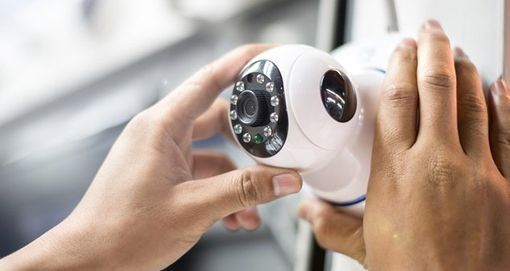 Una persona sostiene una cámara de seguridad en sus manos.
