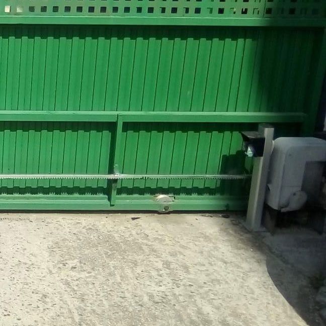 Una puerta corrediza verde con un motor conectado a ella.