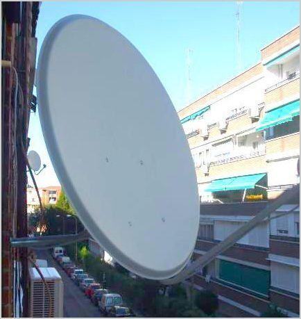 Una antena parabólica está montada en el lateral de un edificio.