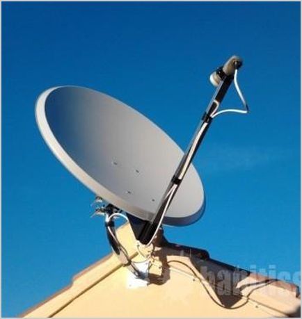 Una antena parabólica en la parte superior de un edificio con un cielo azul de fondo.