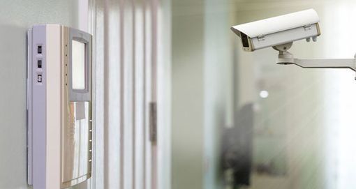 Una cámara de seguridad está colgada en una pared al lado de una puerta.