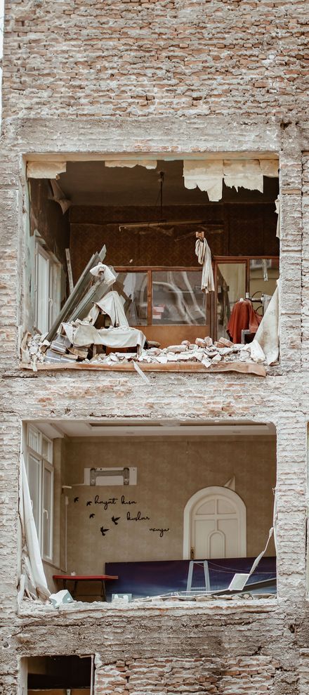 Ventana de la tienda rota con escombros destrozados y una habitación parcialmente intacta en el interior.