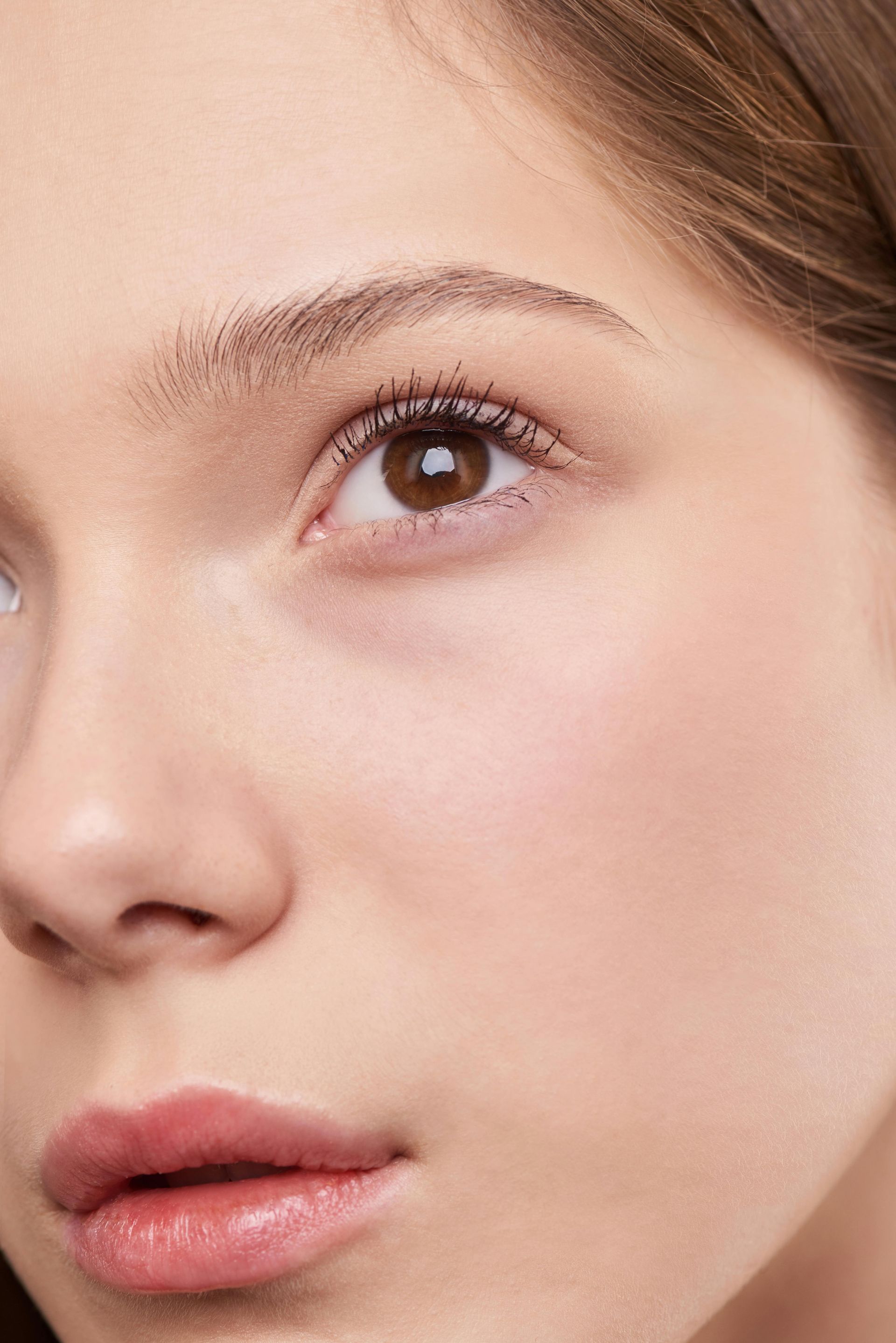 Primer plano del rostro de una persona, centrándose en un ojo, con iluminación suave y maquillaje natural y minimalista.