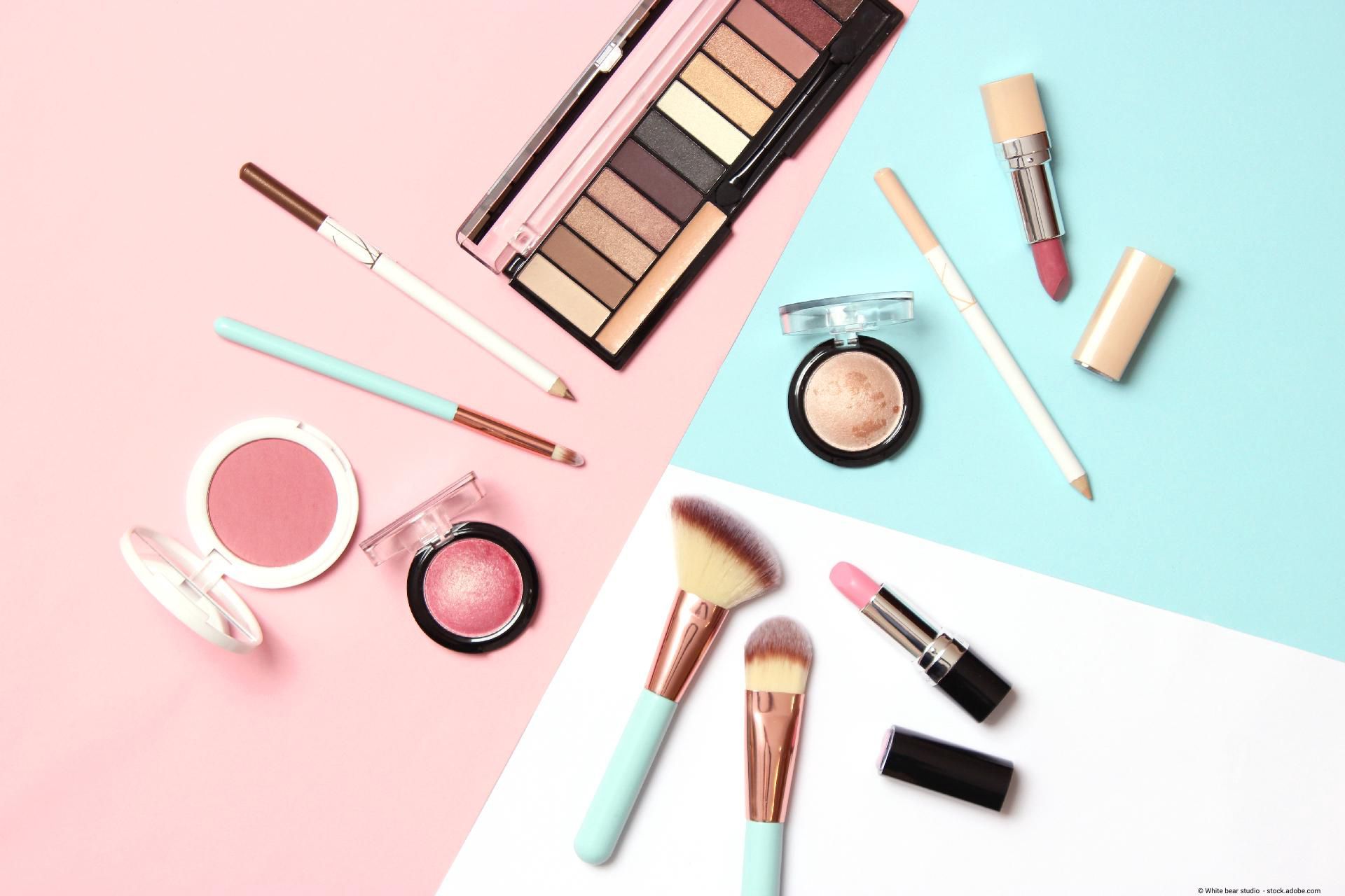 Kosmetikprodukte wie Make-up, Pinsel und Lidschatten auf farbigem Hintergrund