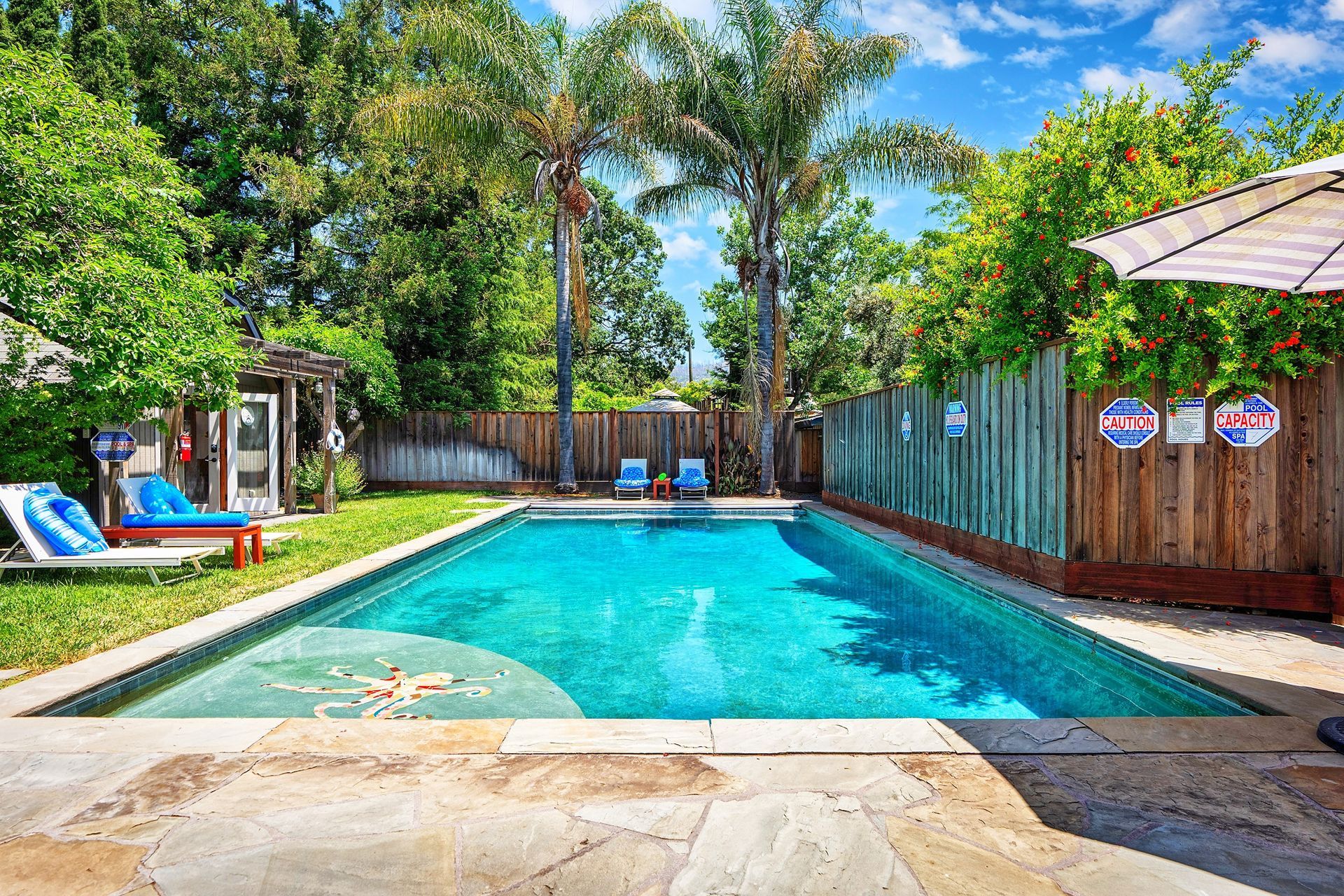 There is a large swimming pool in the backyard of a house.