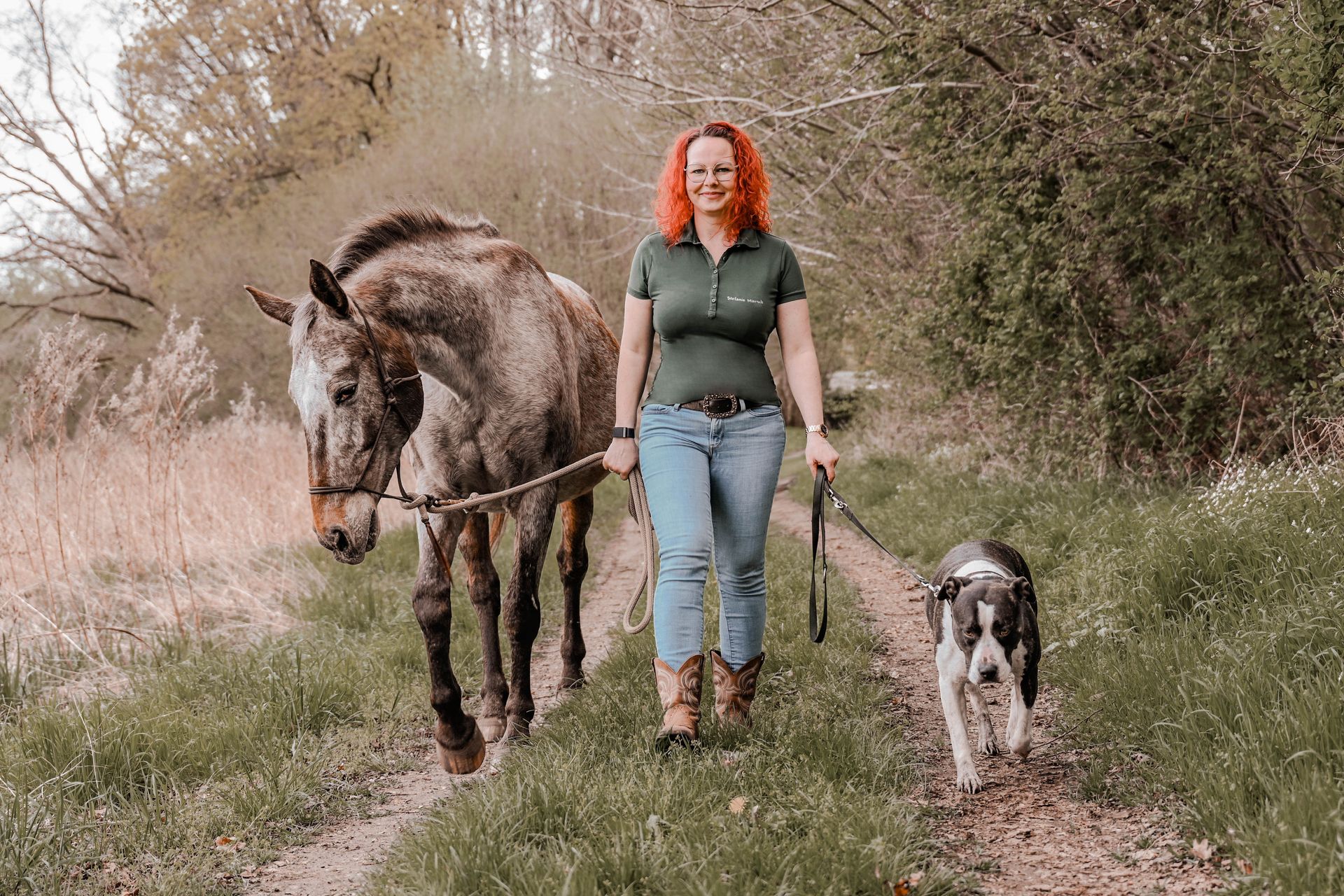 Frau die mit Hund und Pferd spazieren geht