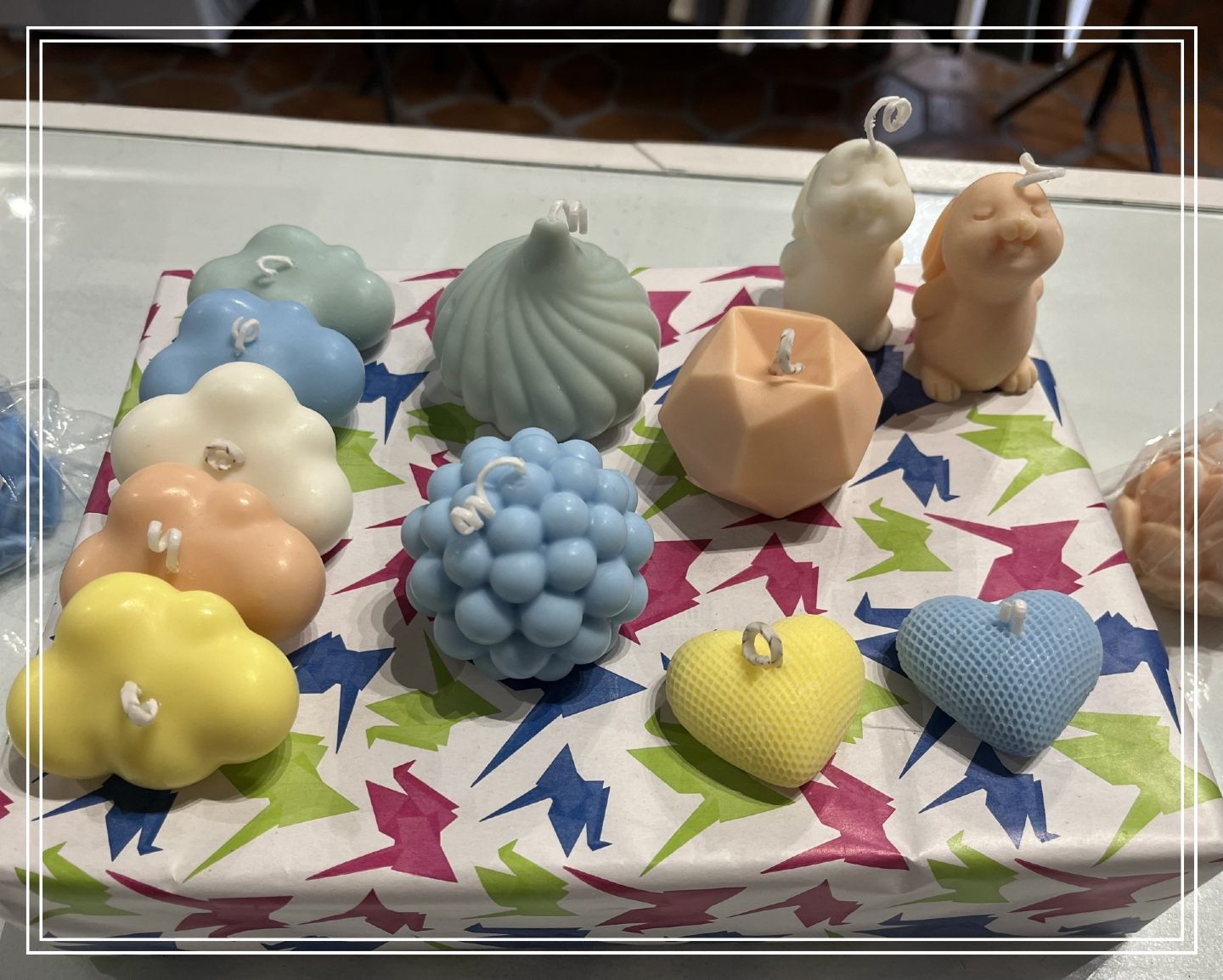 Velas decorativas variadas y coloridas con diseños de nubes, formas, animales y corazones en papel estampado.