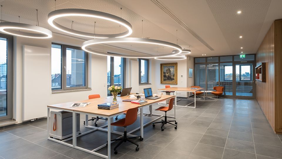 Ein großes Büro mit Tischen und Stühlen und vielen Fenstern.