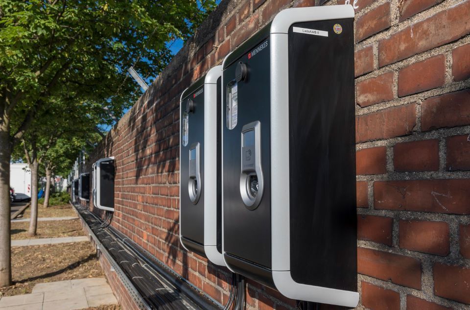 Eine Reihe von Ladestationen für Elektrofahrzeuge an einer Backsteinmauer.