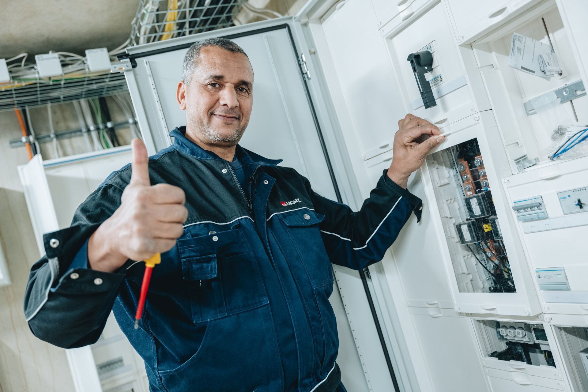 Ein Elektriker hält einen Haufen Kabel und Werkzeuge in der Hand.