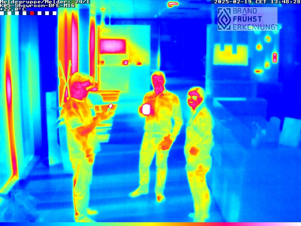 Ein Wärmebild von drei Personen, die nebeneinander in einem Raum stehen.