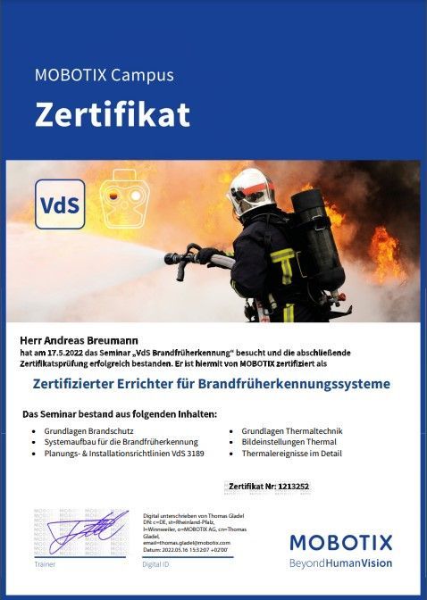 Ein Feuerwehrmann hält einen Schlauch vor ein Feuer.