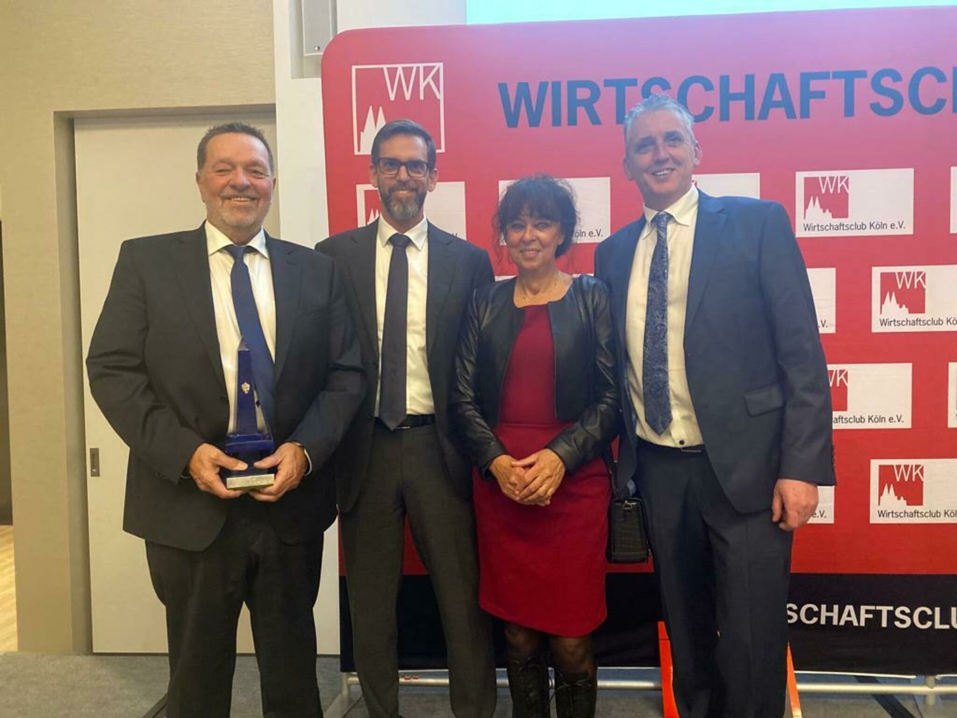 Eine Gruppe von Menschen steht vor einem Schild mit der Aufschrift „Wirtschafts