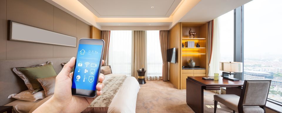 Eine Person hält in einem Hotelzimmer ein Smartphone in der Hand.