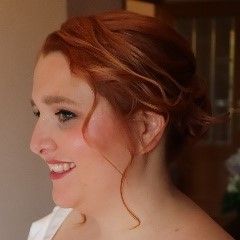 Una mujer con cabello rojo está sonriendo y viste una camisa blanca.