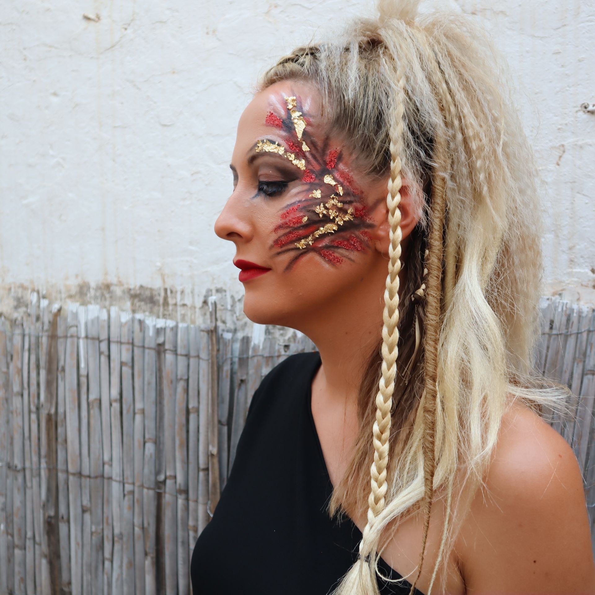 Una mujer con rastas y pintura facial en la cara.