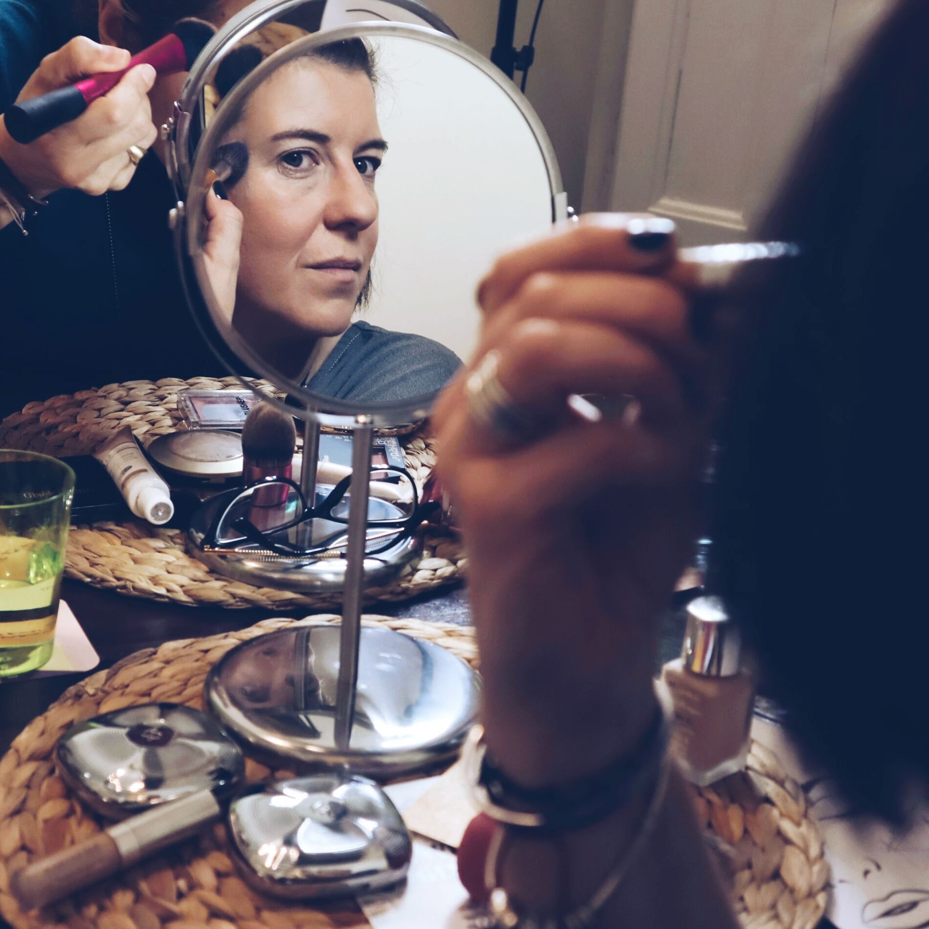 Una mujer se está maquillando la cara frente a un espejo.