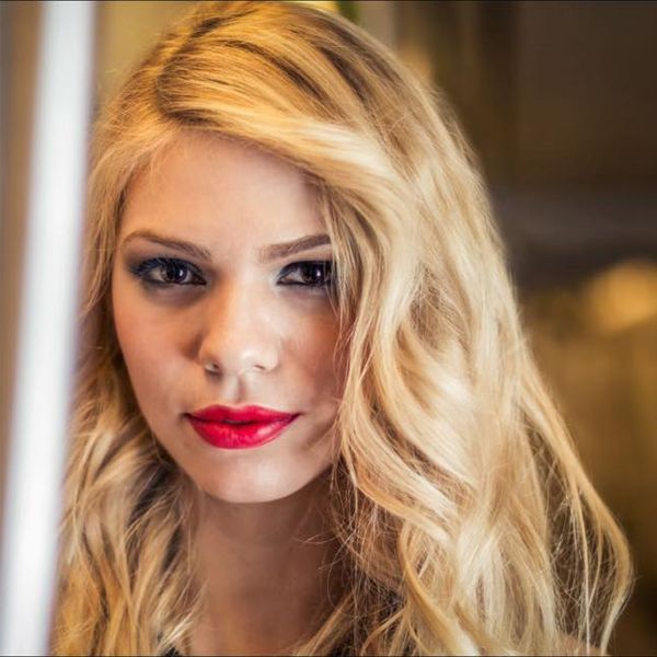 Una mujer con cabello rubio y labios rojos mira a la cámara.