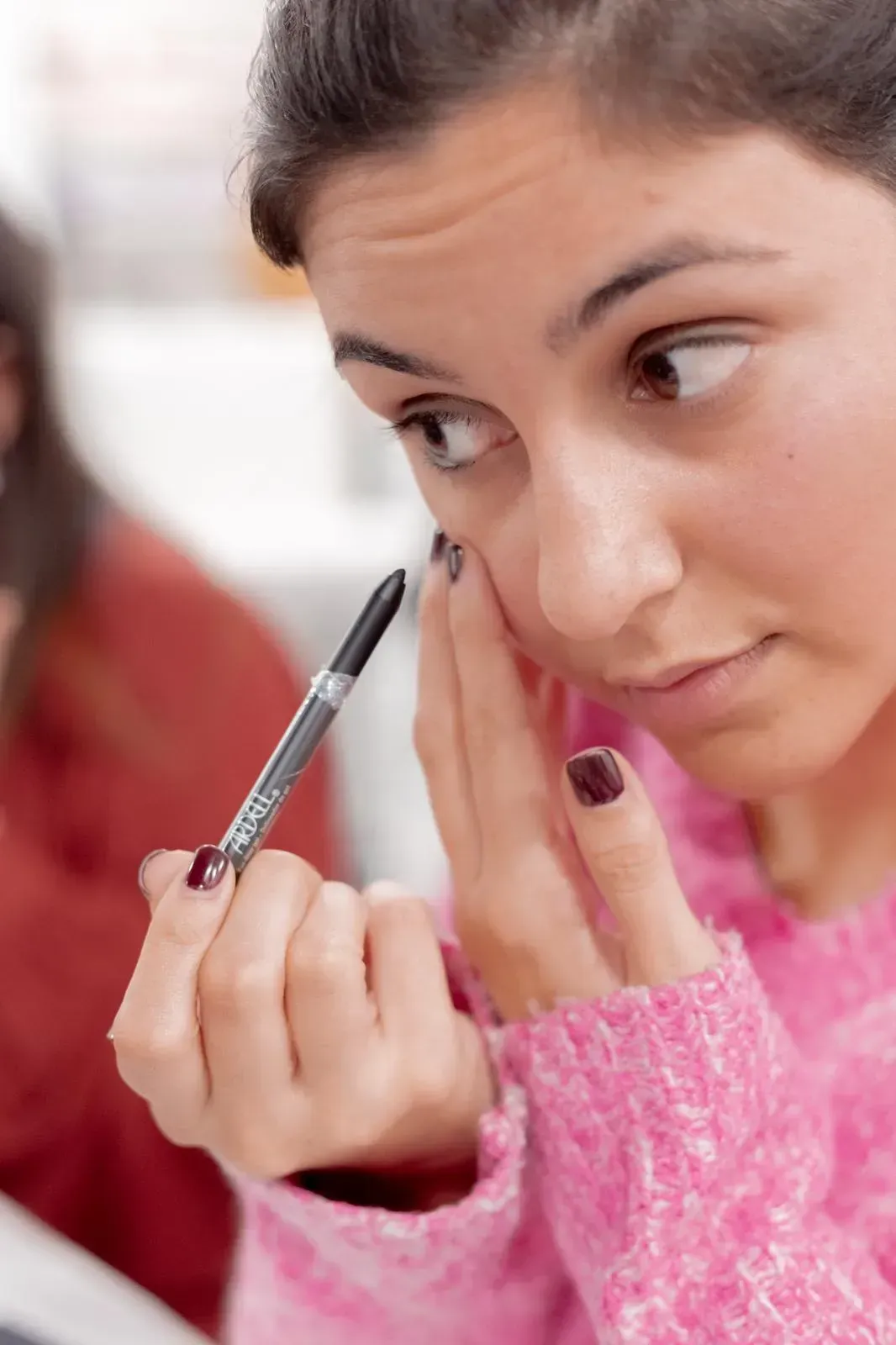 Una mujer se aplica maquillaje en la cara con un bolígrafo.