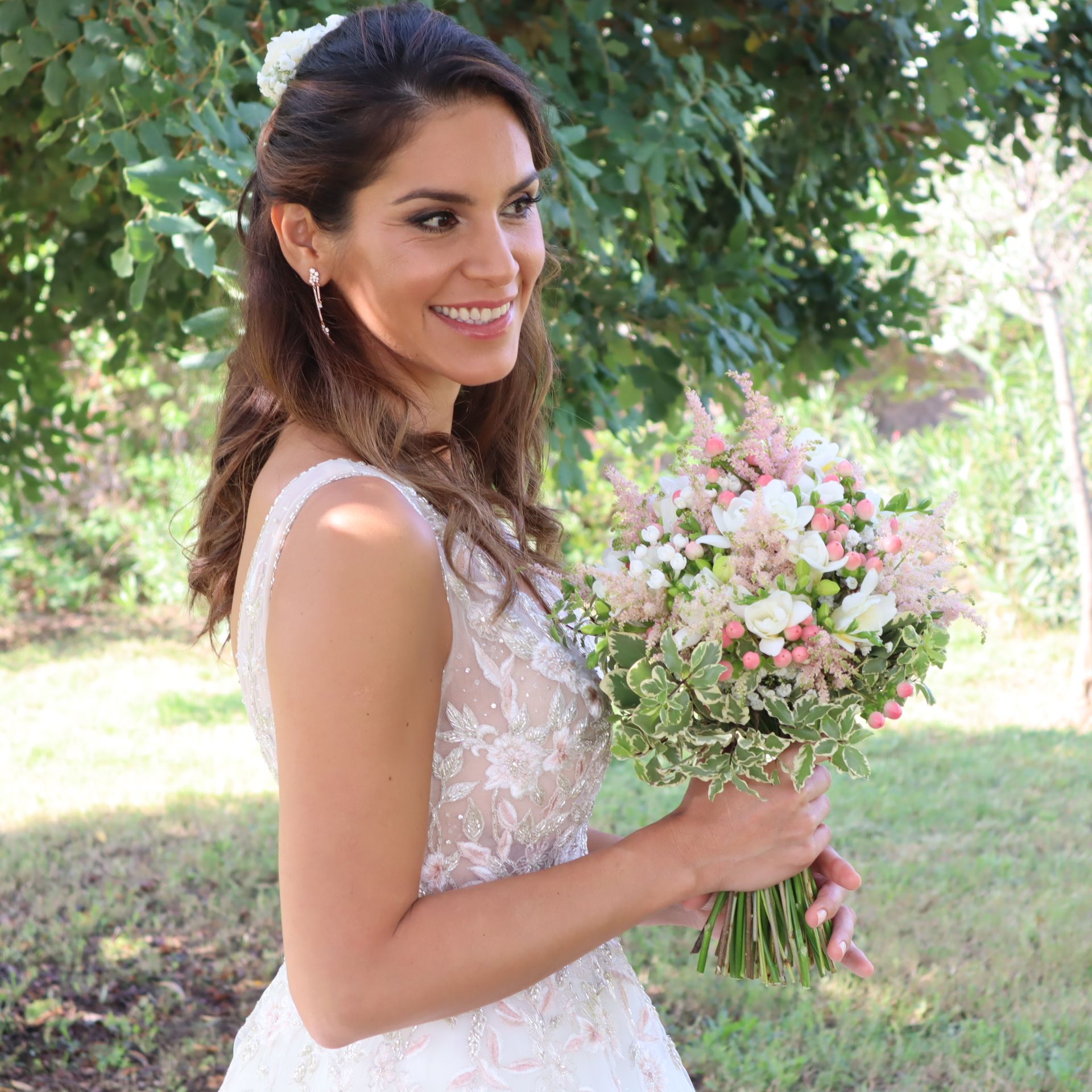 Una mujer con un vestido de novia sostiene un ramo de flores.