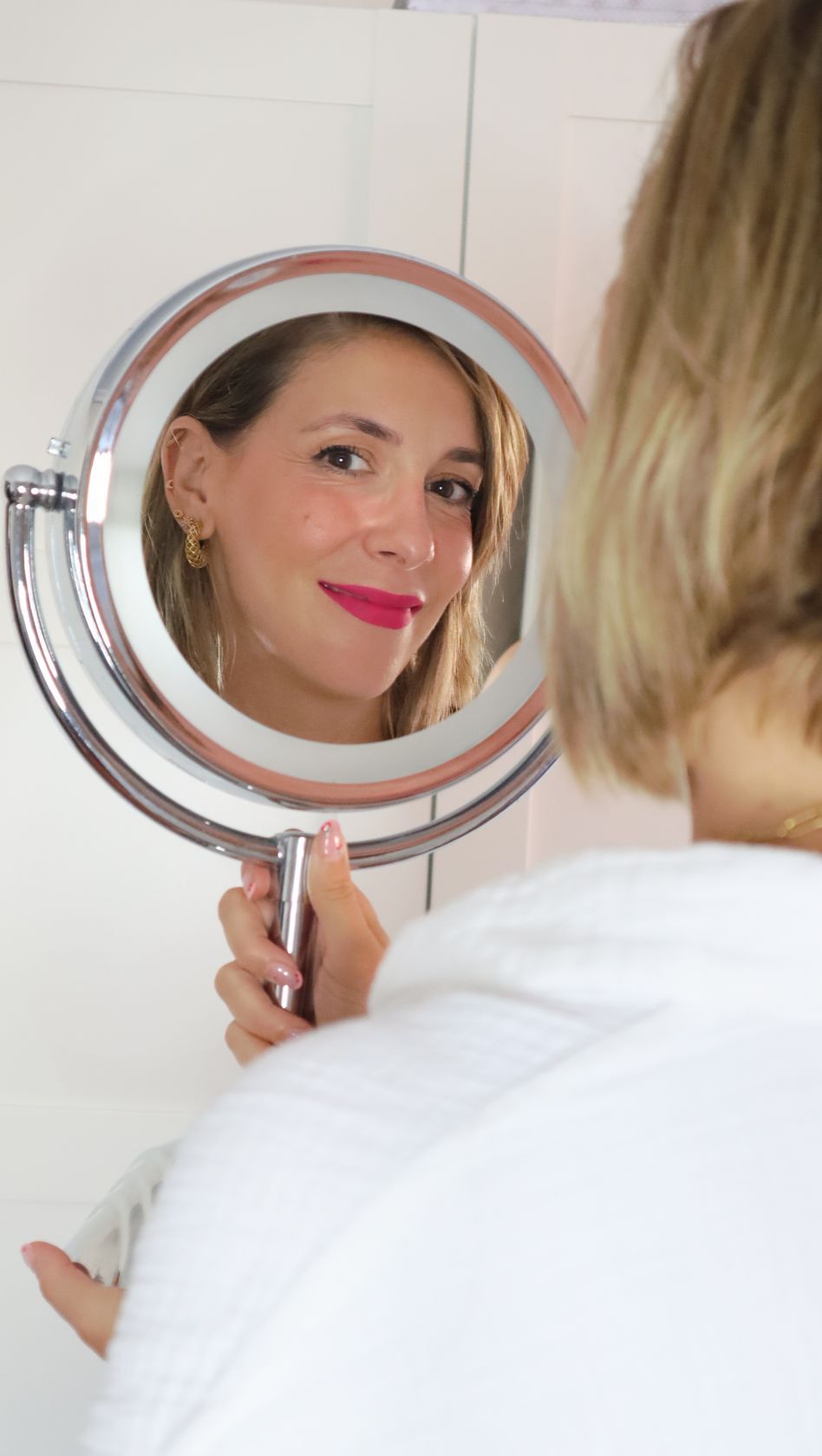 Una mujer se mira su reflejo en un espejo.