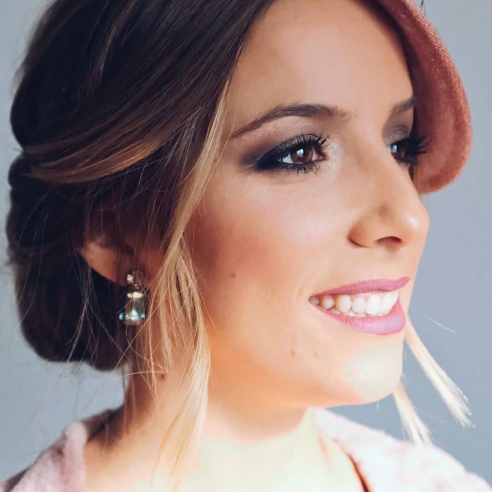 Un primer plano de una mujer con pendientes y sonriendo.