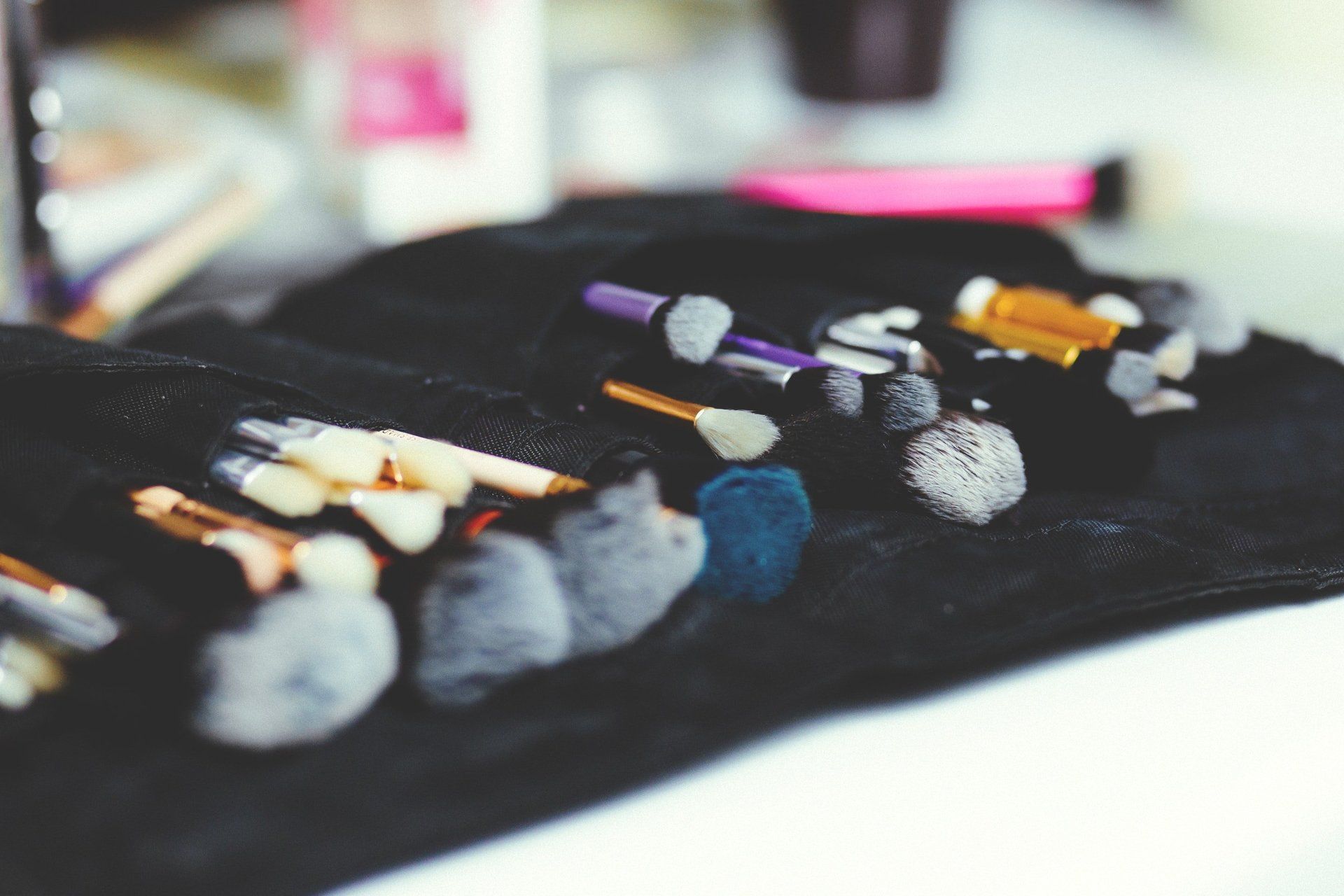 Un montón de pinceles de maquillaje están sobre un paño negro sobre una mesa.