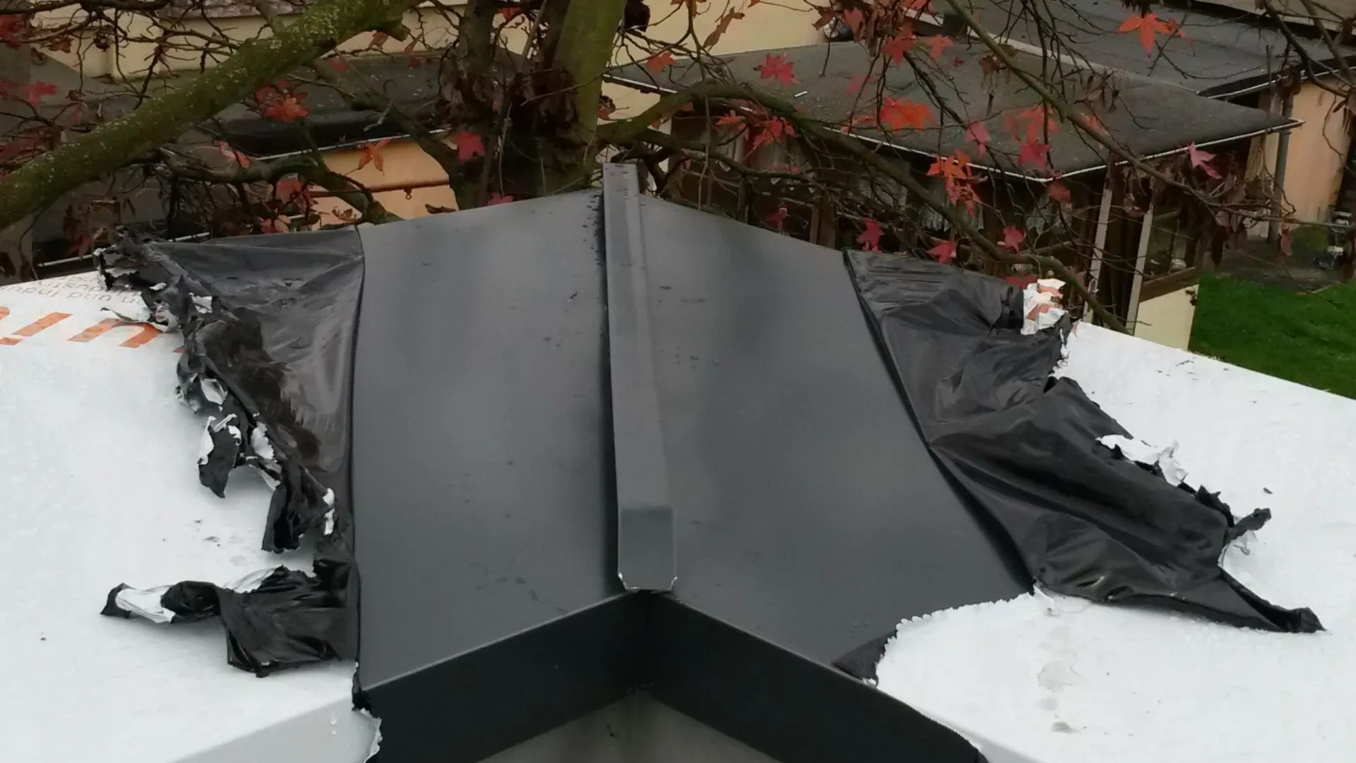 Auf einem weißen Dach liegt eine schwarze Plane.