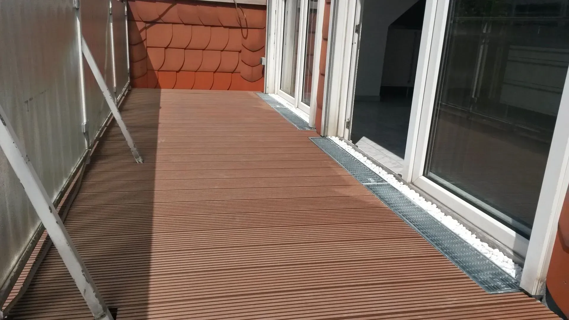 Ein Balkon mit Holzboden und Glasschiebetüren.