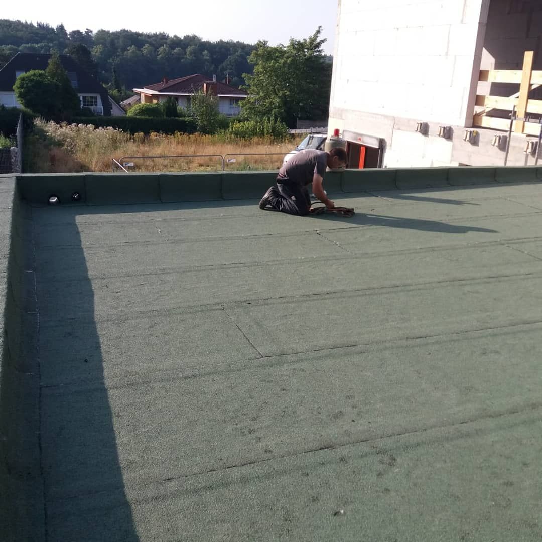 Abdichtungsarbeit mit einem Mitarbeiter auf dem Dach.