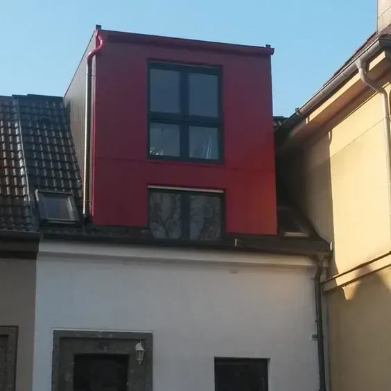 Ein Haus mit ausgebautem Dacht und roter Fassade.