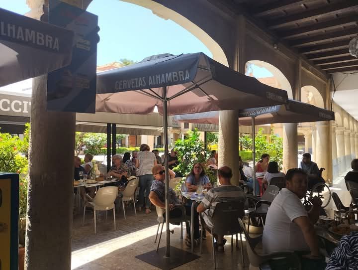 Un grupo de personas están sentadas en mesas bajo sombrillas en un restaurante.
