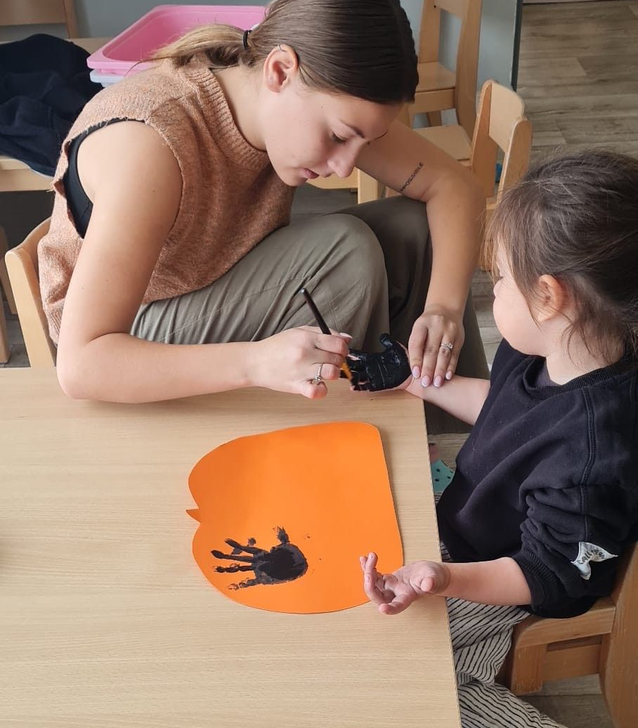 Une femme tient un bébé près d'une colonne à bulles. La colonne est illuminée de lumières colorées.