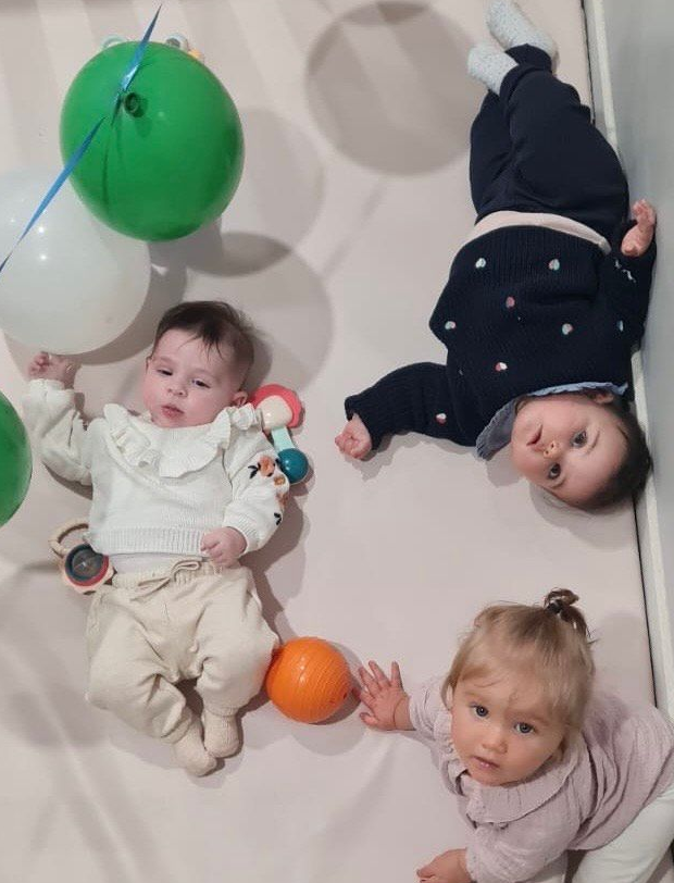 Un enfant sur un toboggan bleu, vêtu d'un t-shirt à rayures bleues et blanches et d'un jean, regarde en bas. Une balle rouge se trouve sur les marches.