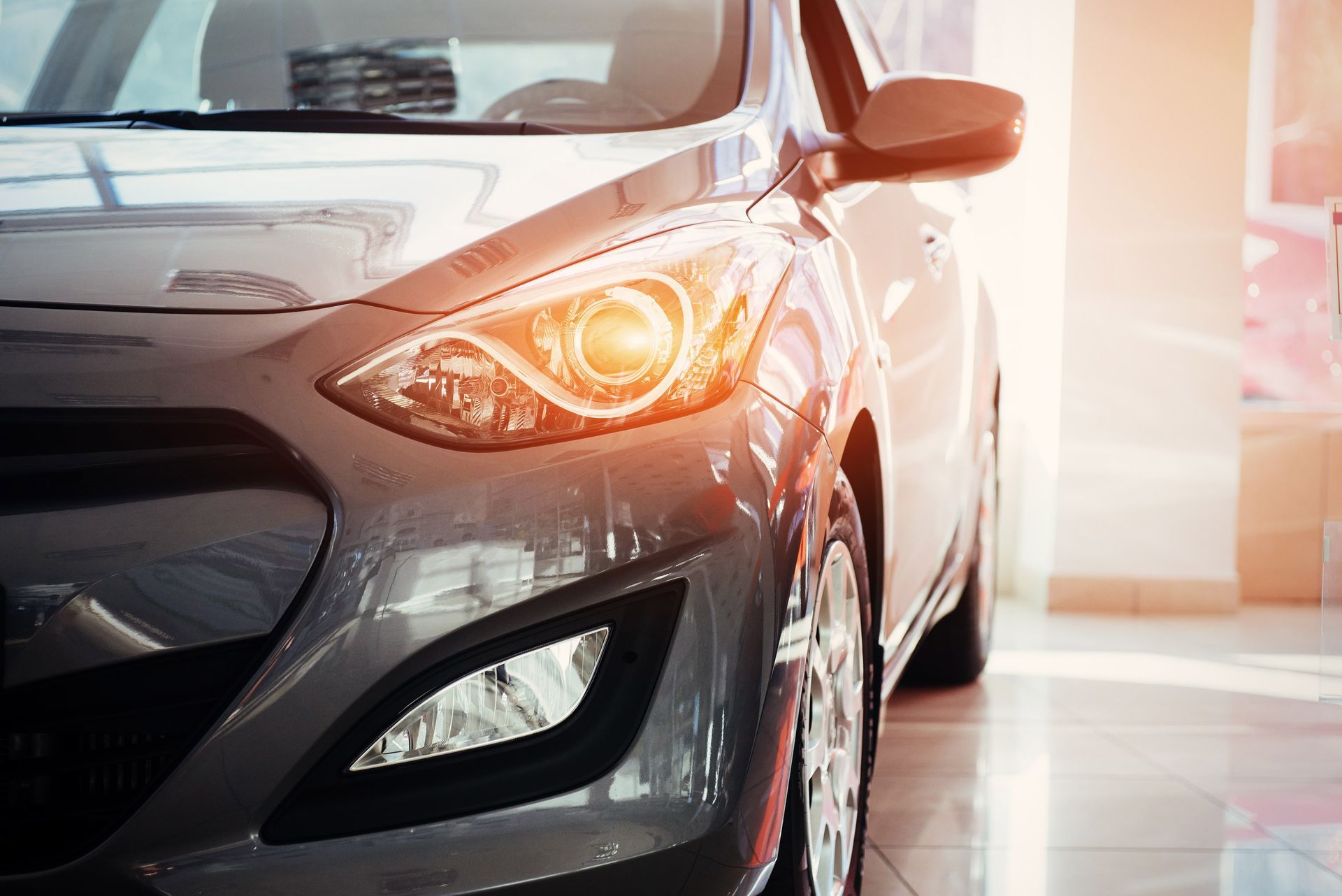 Phare de voiture gris éclairé dans une salle d'exposition.