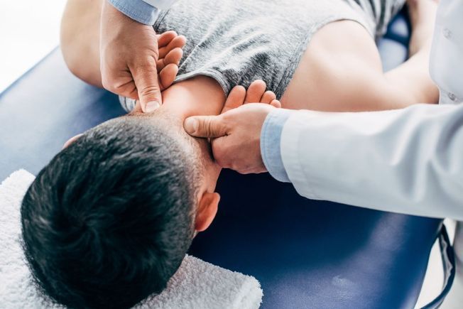 Un hombre está acostado en una mesa recibiendo un masaje de un médico.